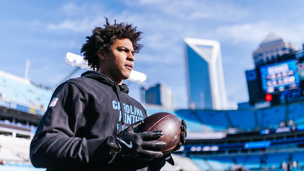 Jalen Coker holding a football on the field at Bank of America Stadium